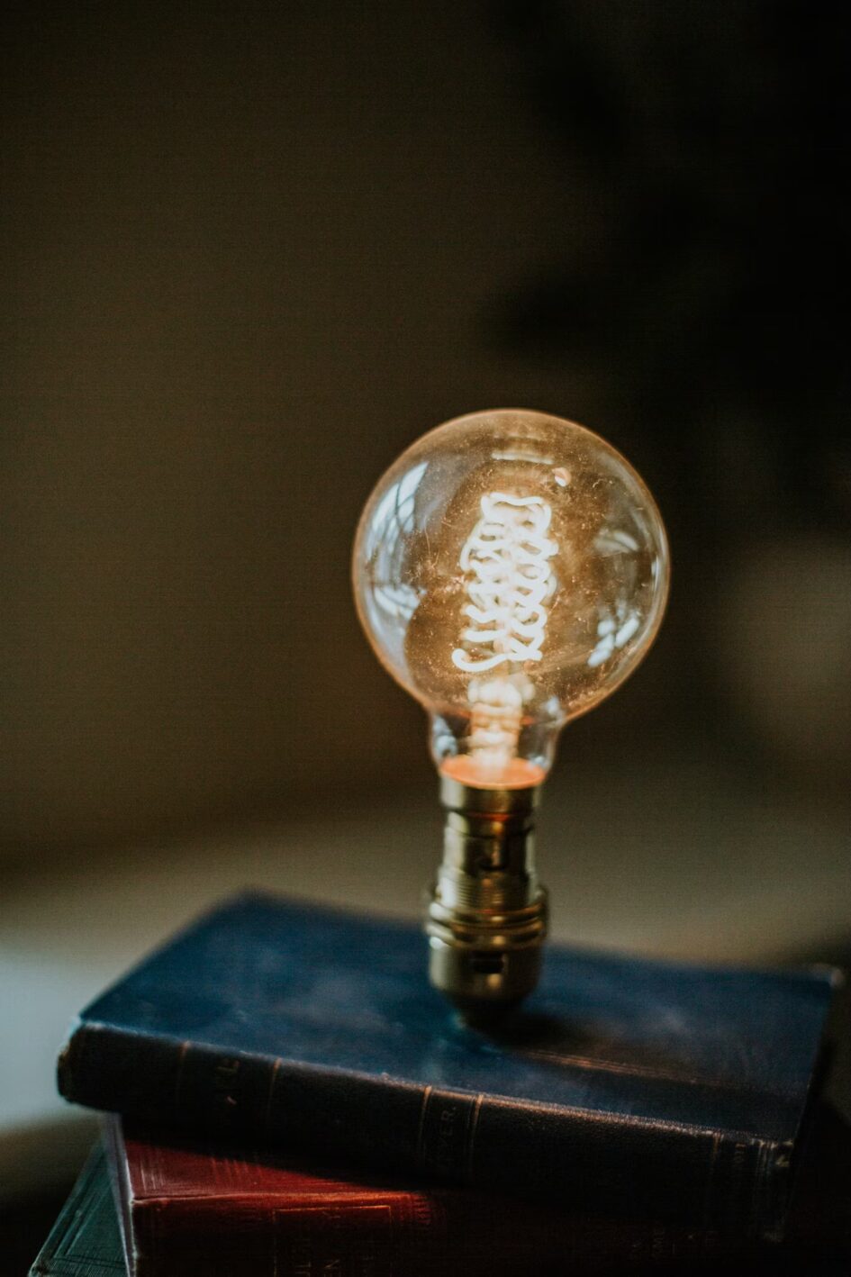 Illuminated light bulb balanced on books